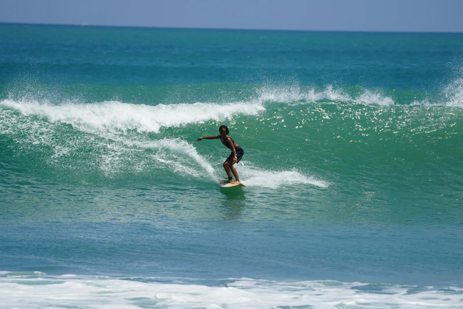 Zazi Betari riding a wave during surf training at Kuta Beach, Bali