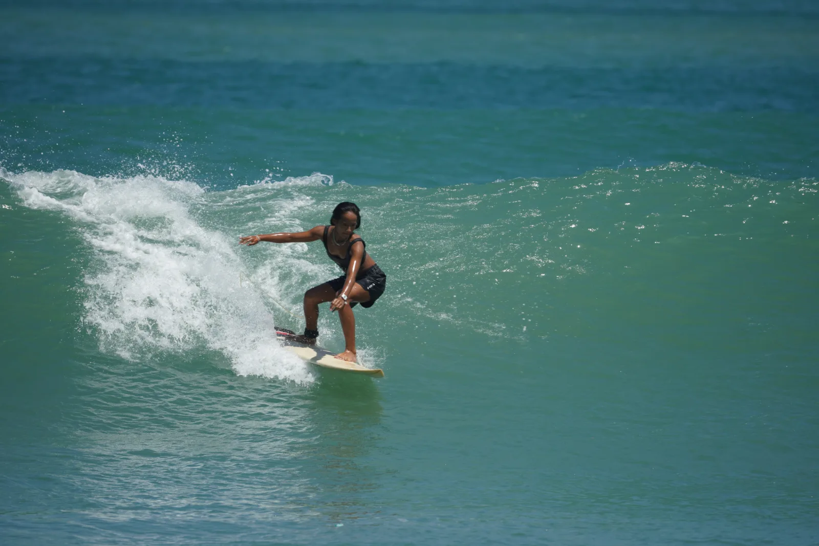 Zazi Betari surfing at Kuta Beach with the wave breaking behind her